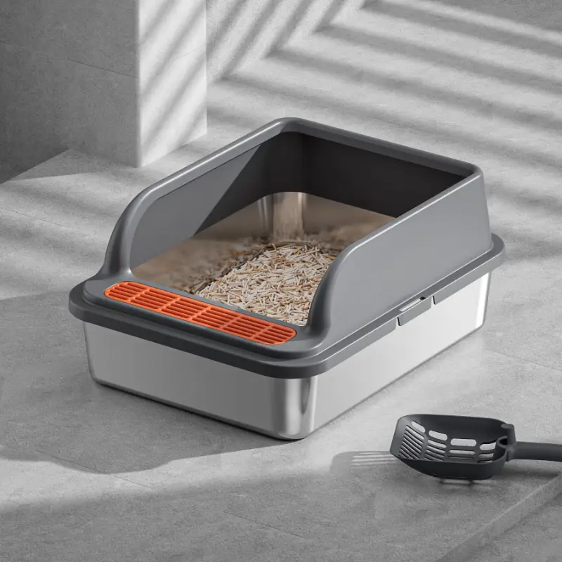 A modern stainless steel cat litter box with a gray frame, paired with a cleaning scoop, placed on a light gray tiled floor